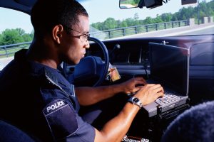African-American police officer using AVL in his police car.